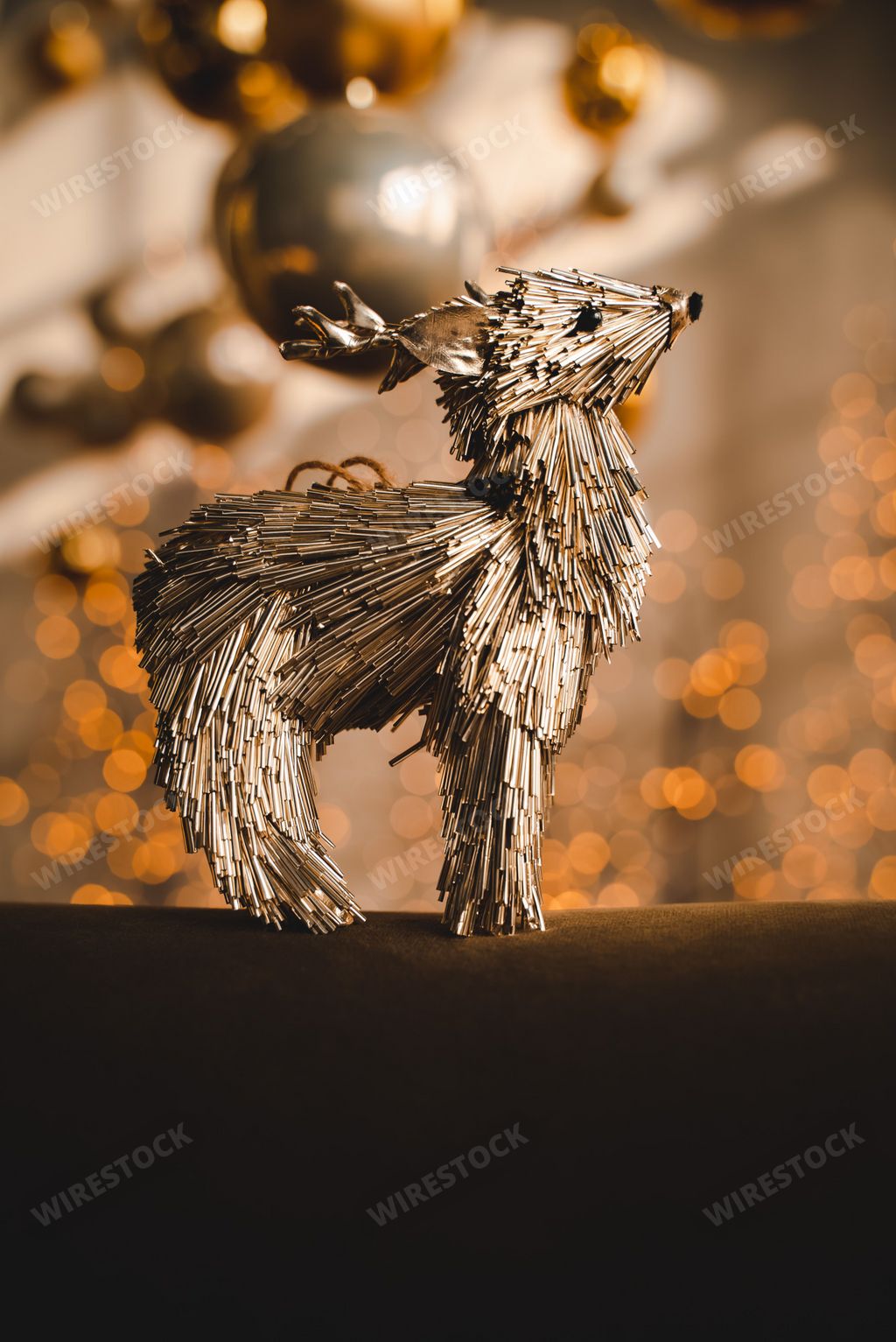 A vertical selective focus shot of a straw reindeer ornament on a bokeh background