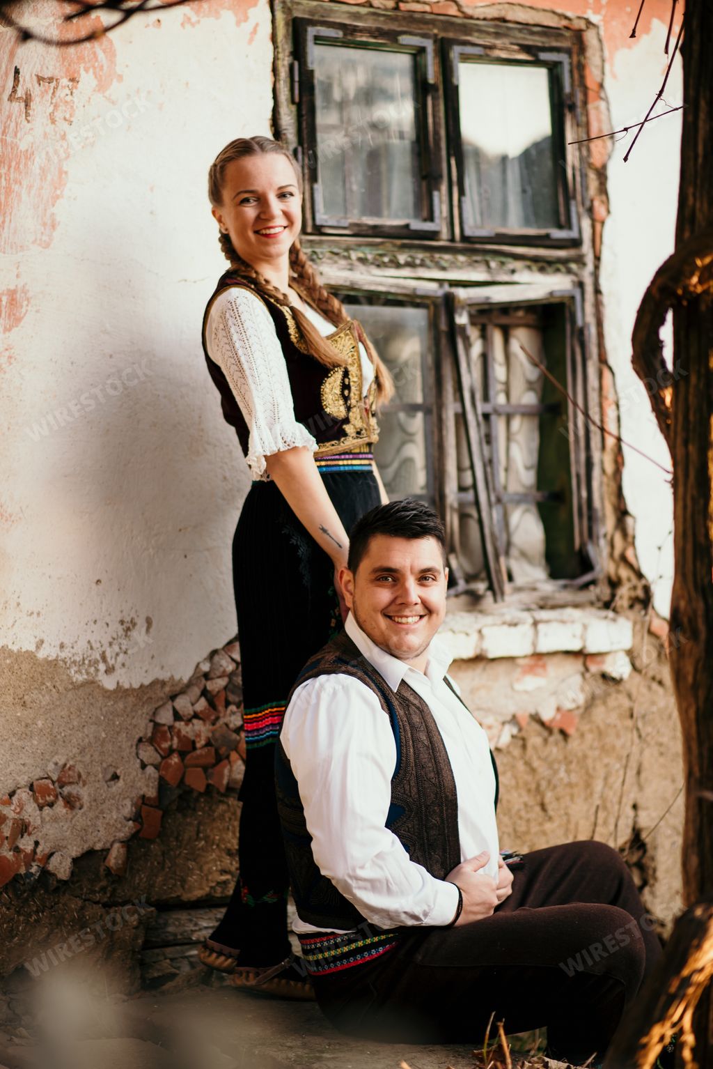 A close-up shot of a young Serbian couple in traditional costume in the field