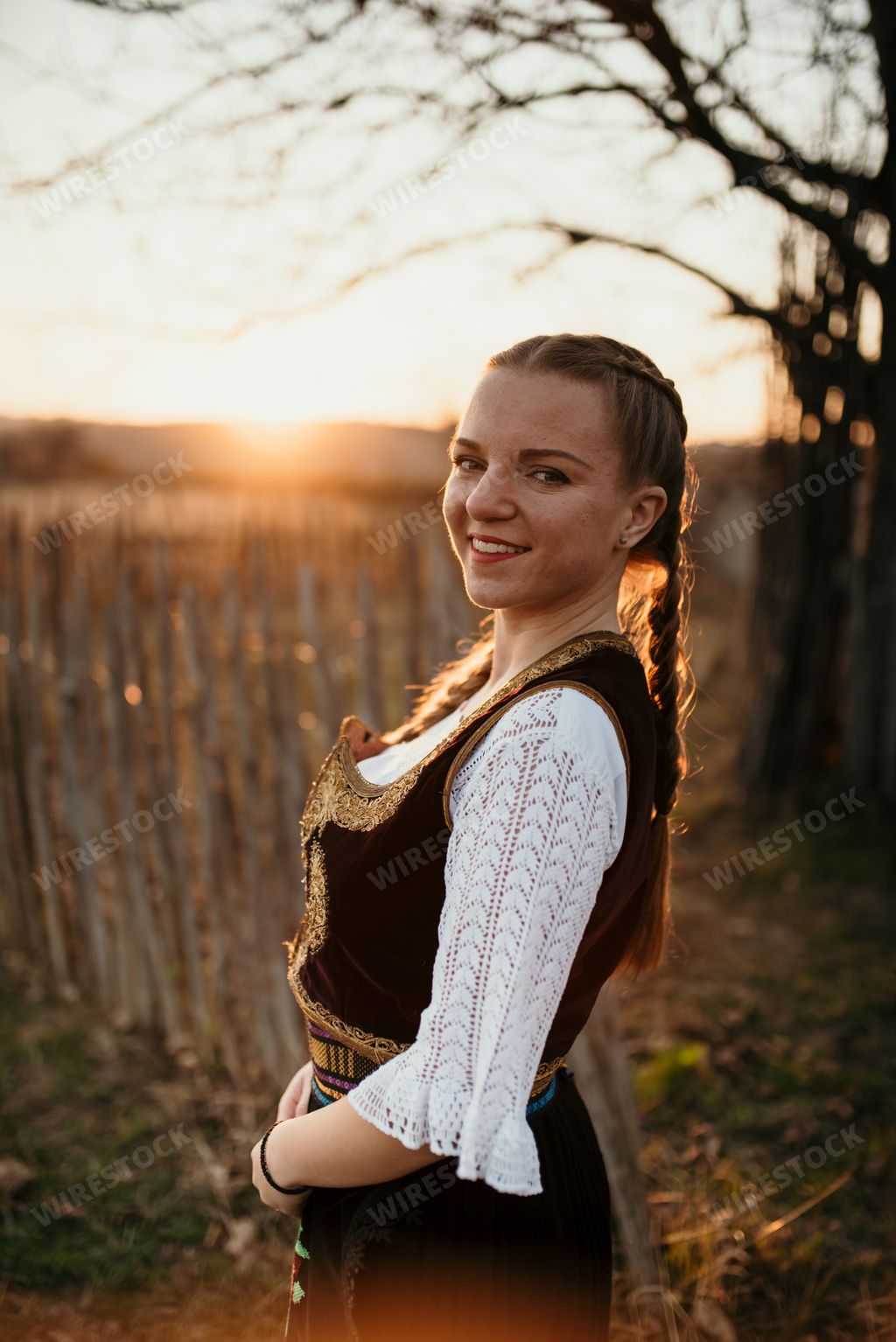 A beautiful shot of a Serbian girl in traditional costume posing for a photo during the sunset