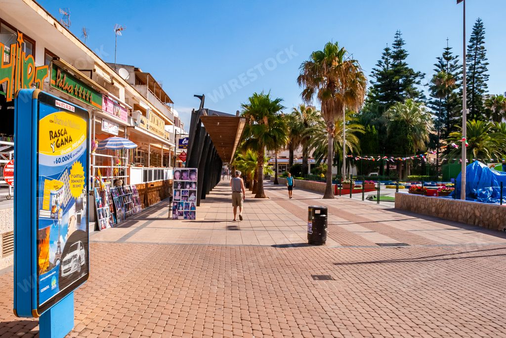A sunny day on the streets in the Center of Cala Millor with retail stores and palm trees in Mallorca, Spain