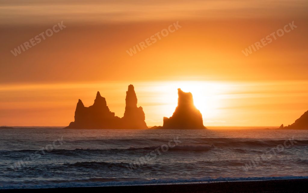 The silhouettes of Reynisdrangar sea stocks in Vik Iceland against the bright golden sunset