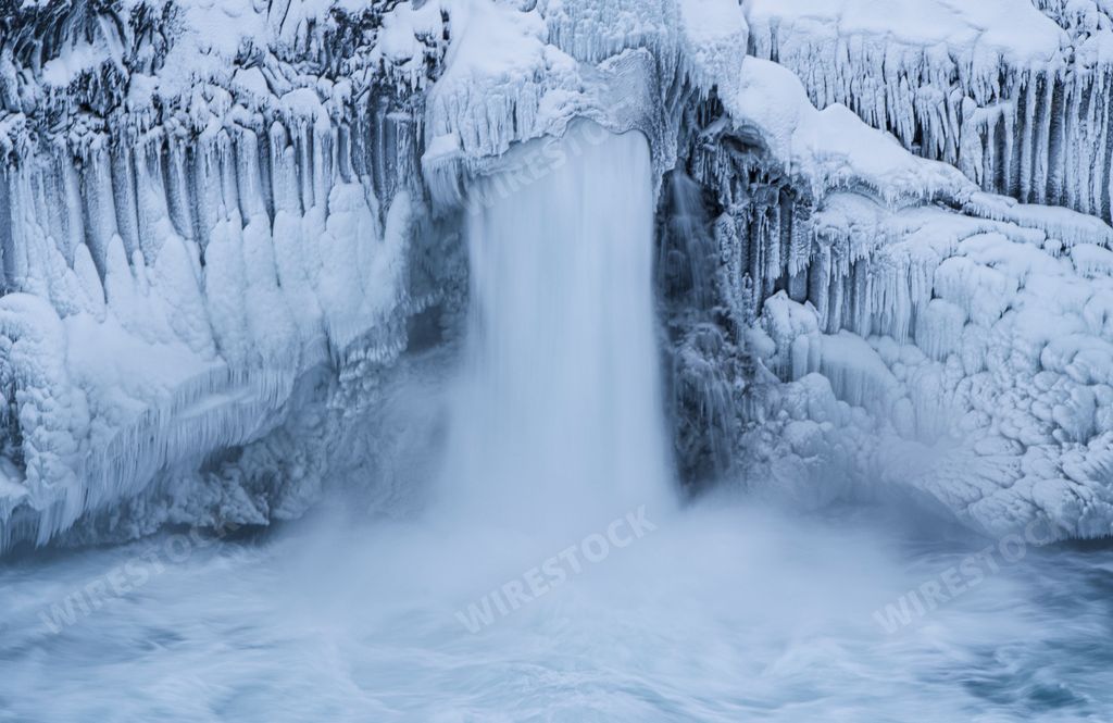 The frozen Aldeyjarfoss waterfall in North Iceland surrounded by frozen rocks