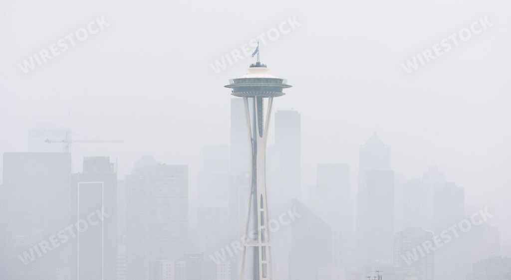 A closeup shot of the Space Needle before Seattle buildings covered in mist