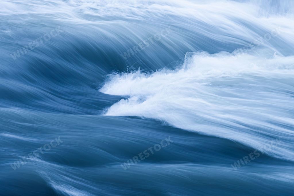 A tranquil scene of the ocean with gentle waves lapping against the rocky shoreline in Iceland