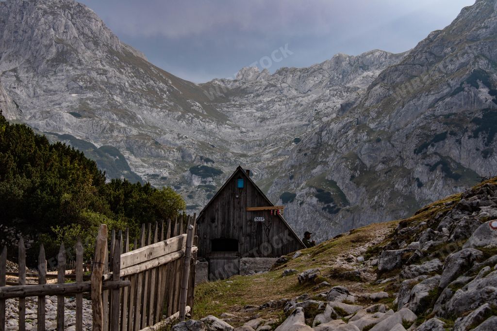 A beautiful nature scene with a cabin in the mountains surrounded by trees