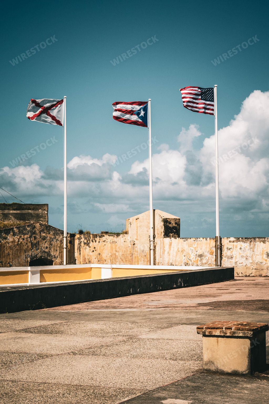 A vertical shot of Puerto Rico, American and Cross of Burgundy flags on the top of El Morro