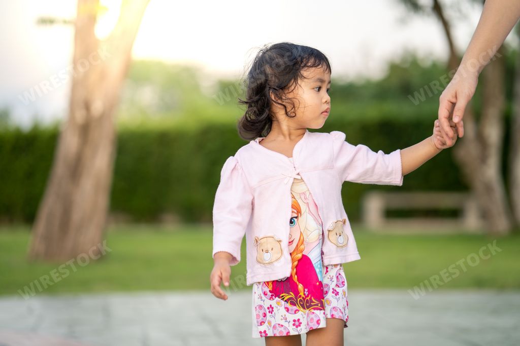 A closeup shot of a Southeast Asian baby girl holding her mother's hand