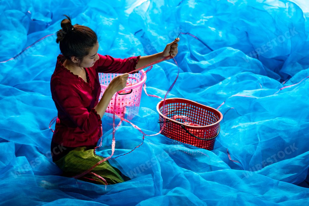 A closeup shot of a beautiful Asian woman sewing the fishnet in Thailand