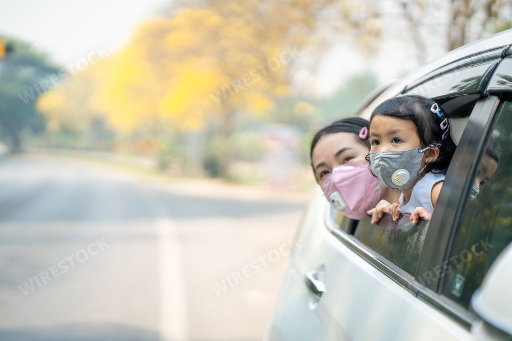 A Thai mother and daughter wearing a face mask seen through car windows