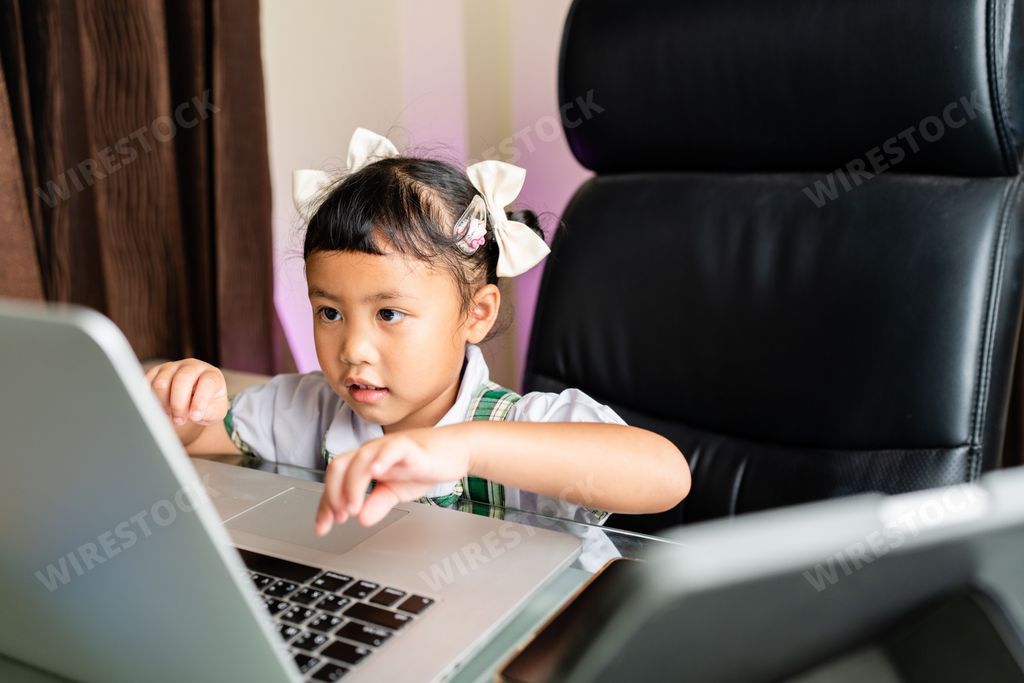 A closeup of a cute southeast Asian girl sitting in front of a laptop