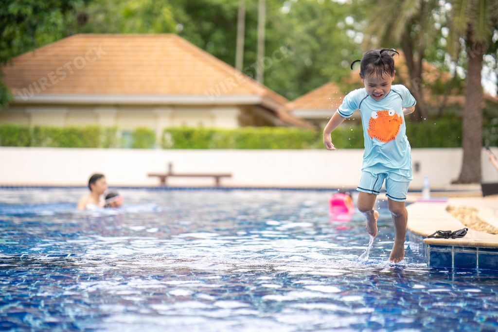 A closeup shot of an Asian child jumping in a swimming pool
