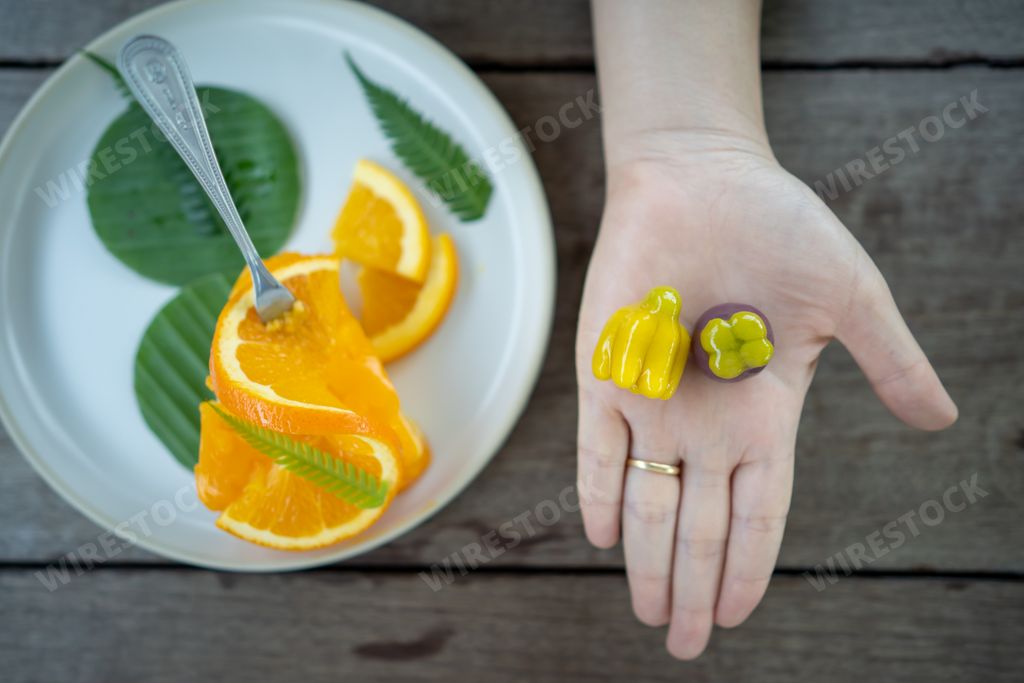 An overhead shot of a female hand with cookies and a plate with sliced orange