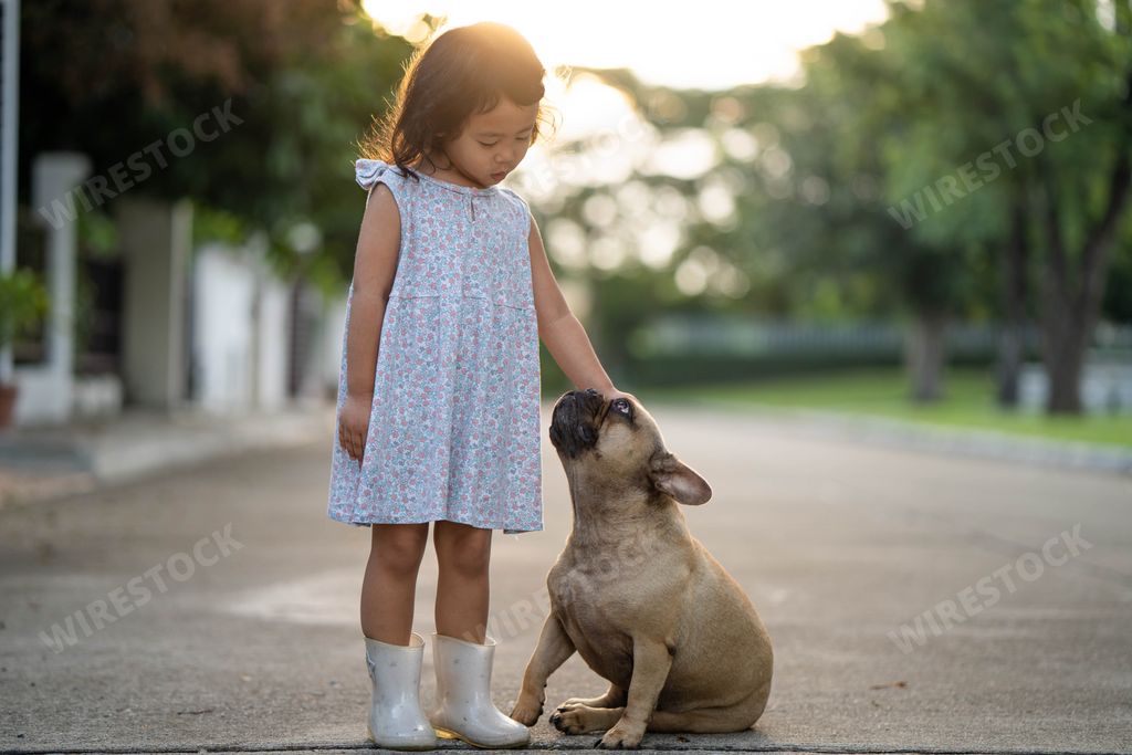 A cute Asian small girl playing with her dog outdoor