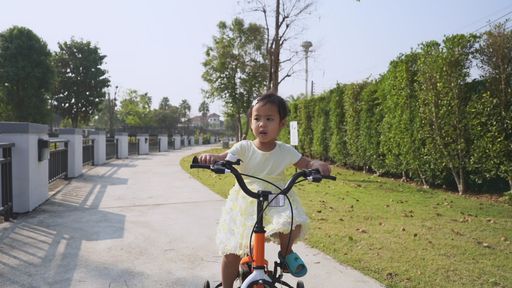 Cute little Asian girl riding a bicycle in the park Stock video | Wirestock