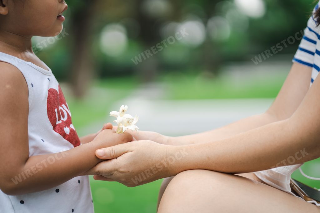 A Southeast Asian female kid giving her mother a bunch of white flowers at the