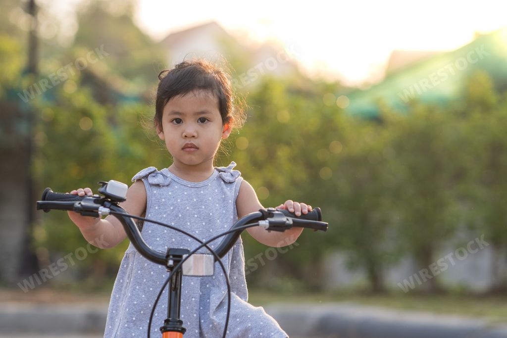 A cute little Thai girl riding a bicycle