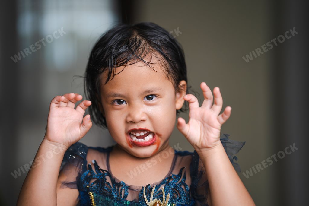 A shallow focus shot of a cute Southeast Asian girl from Thailand in a Halloween costume and makeup