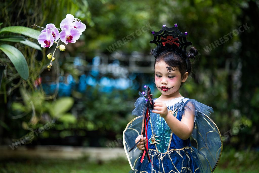 A cute Asian female child posing in a fun witch Halloween costume