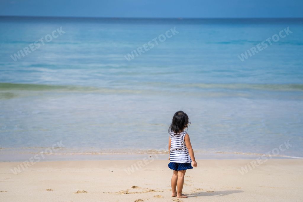A back view of a cute little Thai girl at the beach