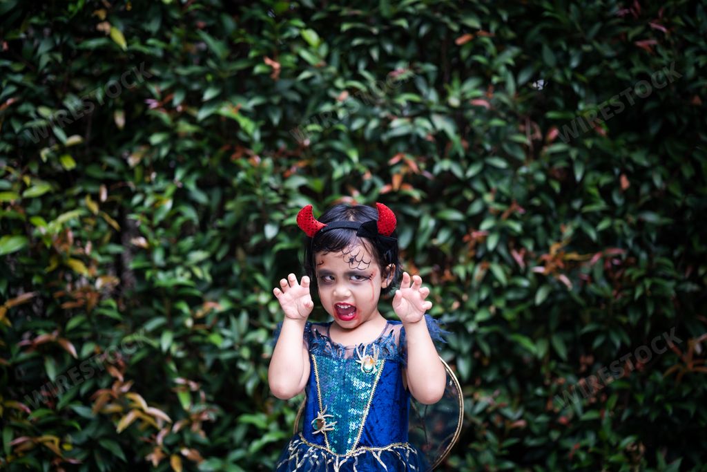 A shallow focus shot of a cute Southeast Asian girl from Thailand in a Halloween costume and makeup