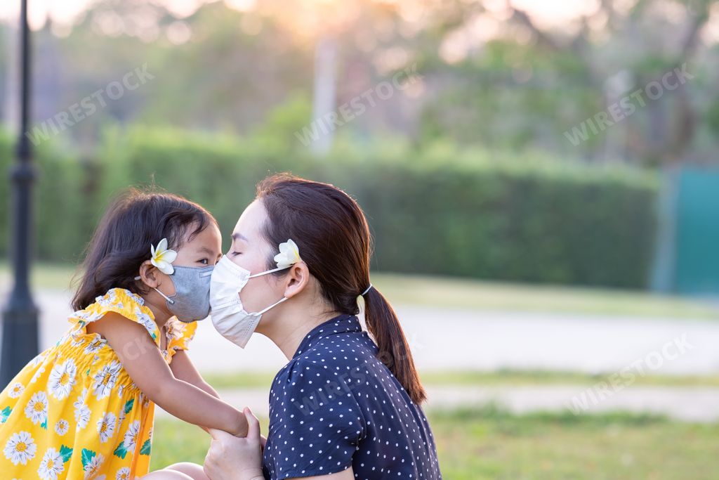 A closeup shot of a cute South Asian child and mother with masks in a garden