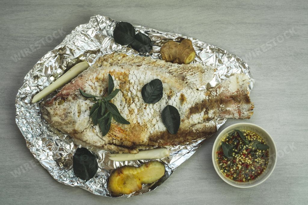 A top view of grilled tilapia with chili sauce next to it