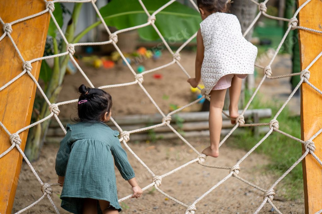 A shot of two little girls playing and climbing a rope net in the playground