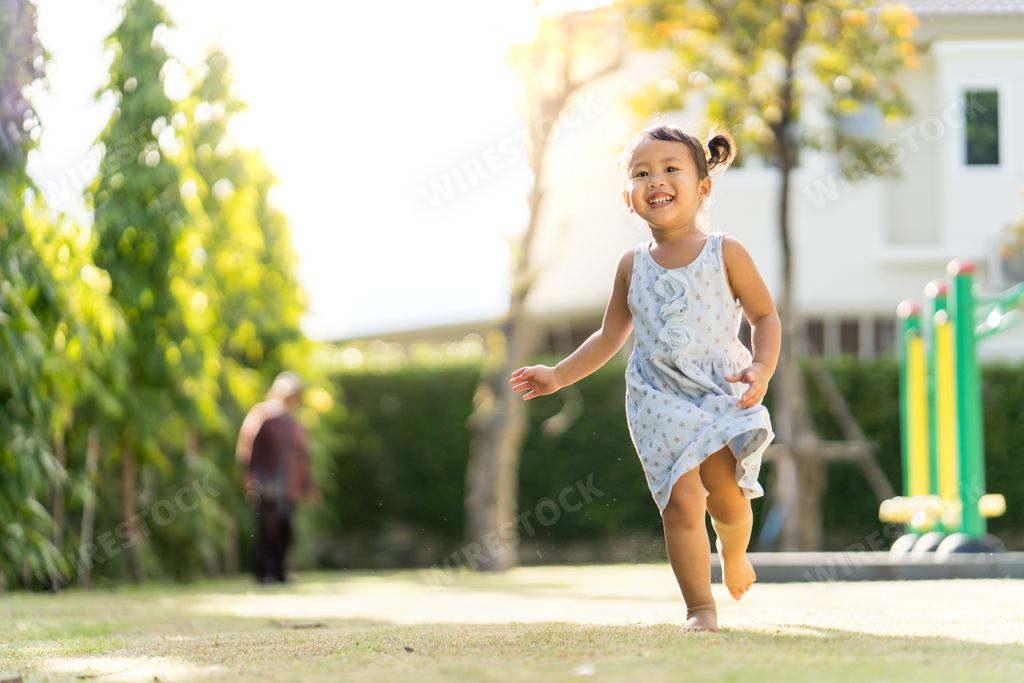 A cute little girl running in the yard.