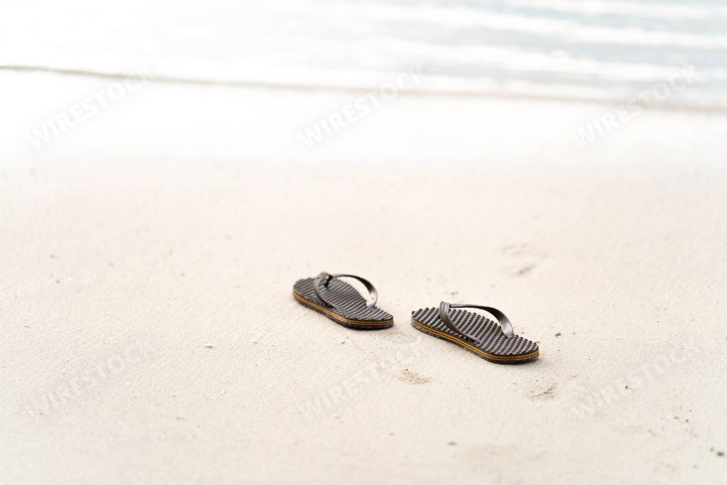 A close-up shot of flip-flops on the beach background.