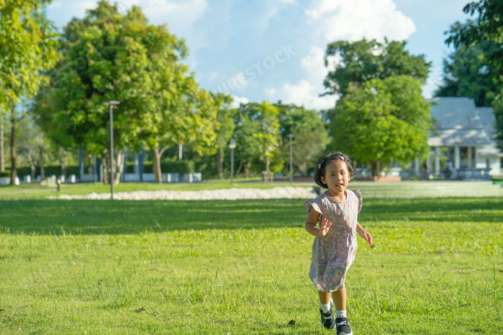 A cute Asian small girl running in a park