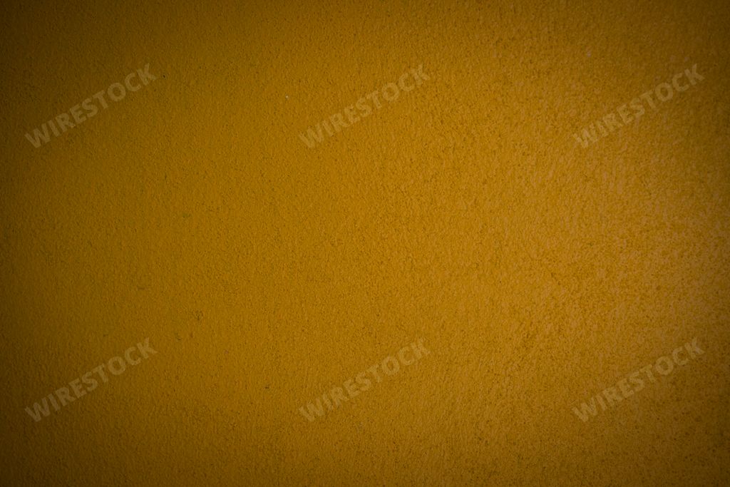 A plain golden yellow wall background - Texture of a rough vibrant yellow wall with dark corners