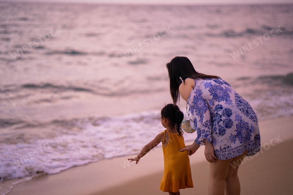 A closeup of a mother with her daughter on the beach during sunset.