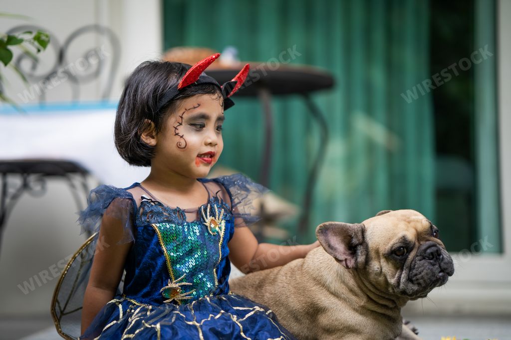 A cute Southeast Asian girl from Thailand in a Halloween costume and makeup with her French Bulldog