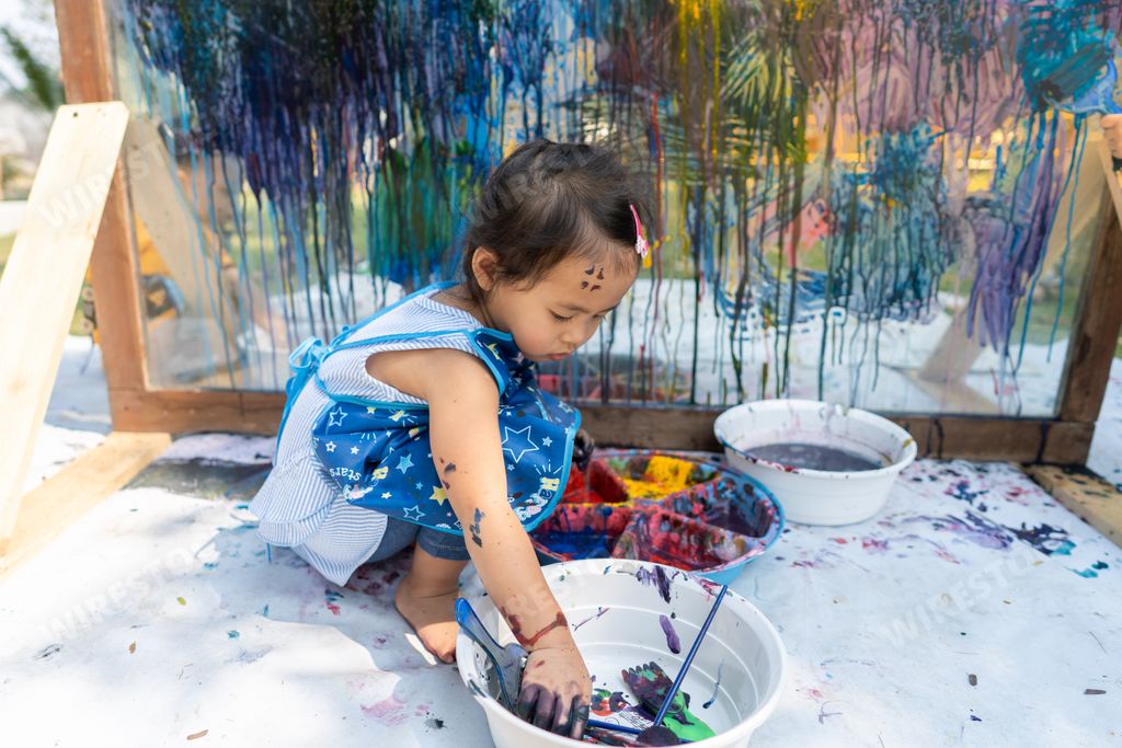 A cute little Thai girl painting on a glass