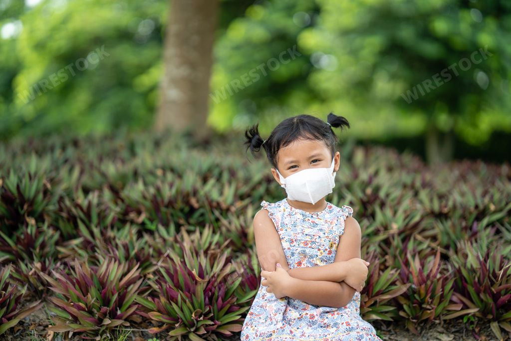 A cute little Thai girl wearing a face mask in the park