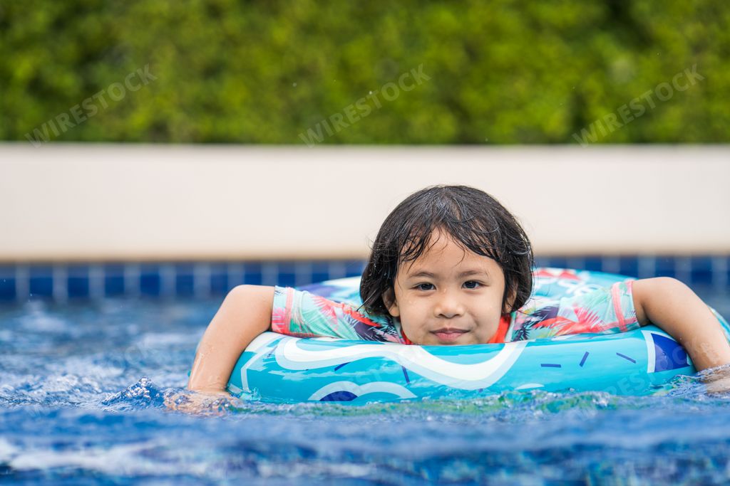A cute Asian small girl swimming in a pool