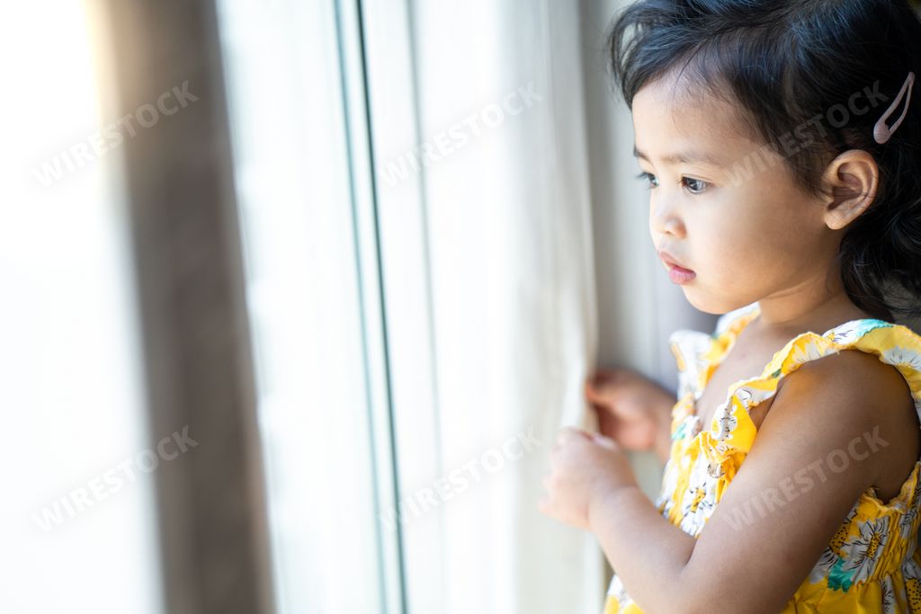 A cute little Thai girl looking out of a wind