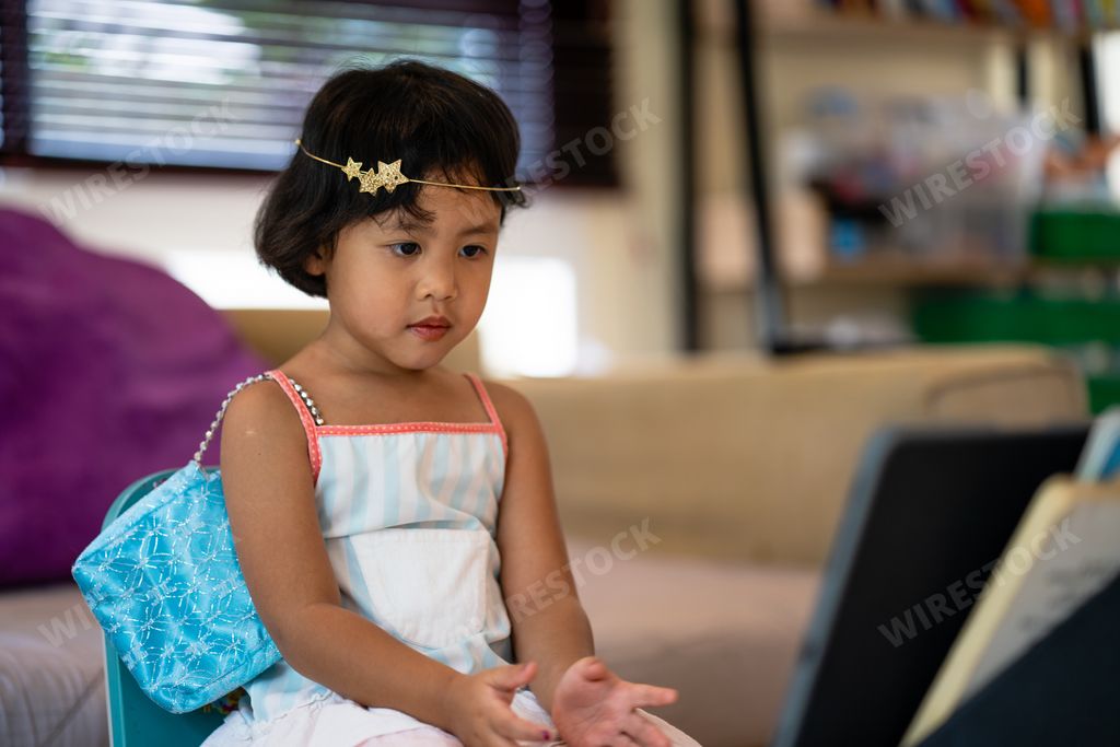 A closeup shot of a Southeast Asian little kid sitting on a chair