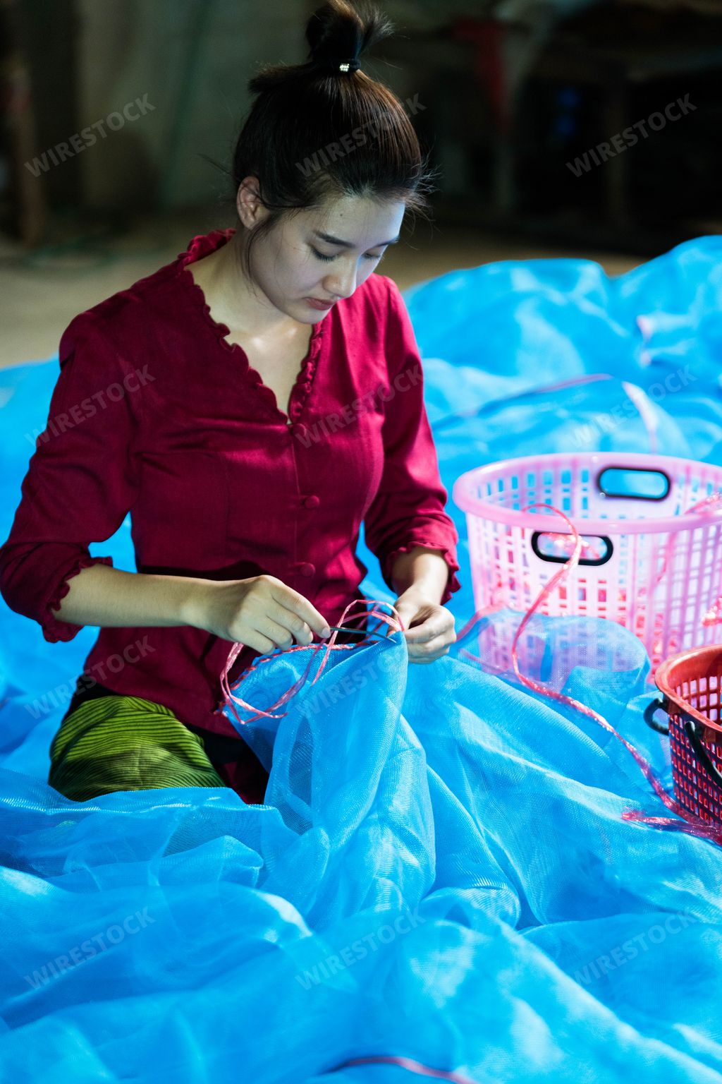 A young Asian woman sewing the fishnet at the fishing village