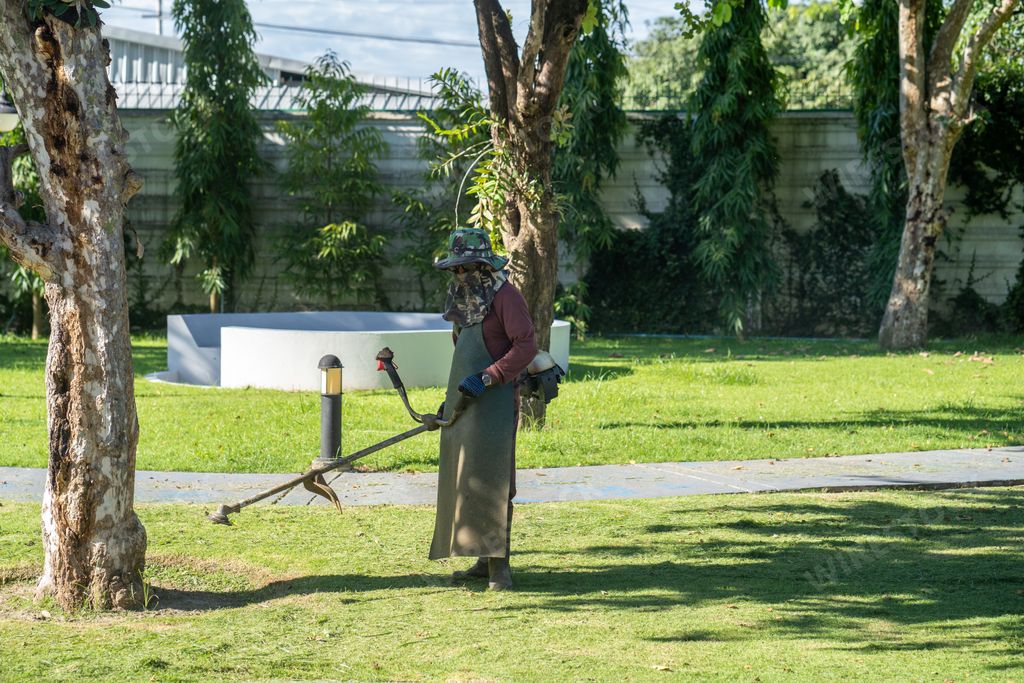 A man using a mower cutting grass in the park