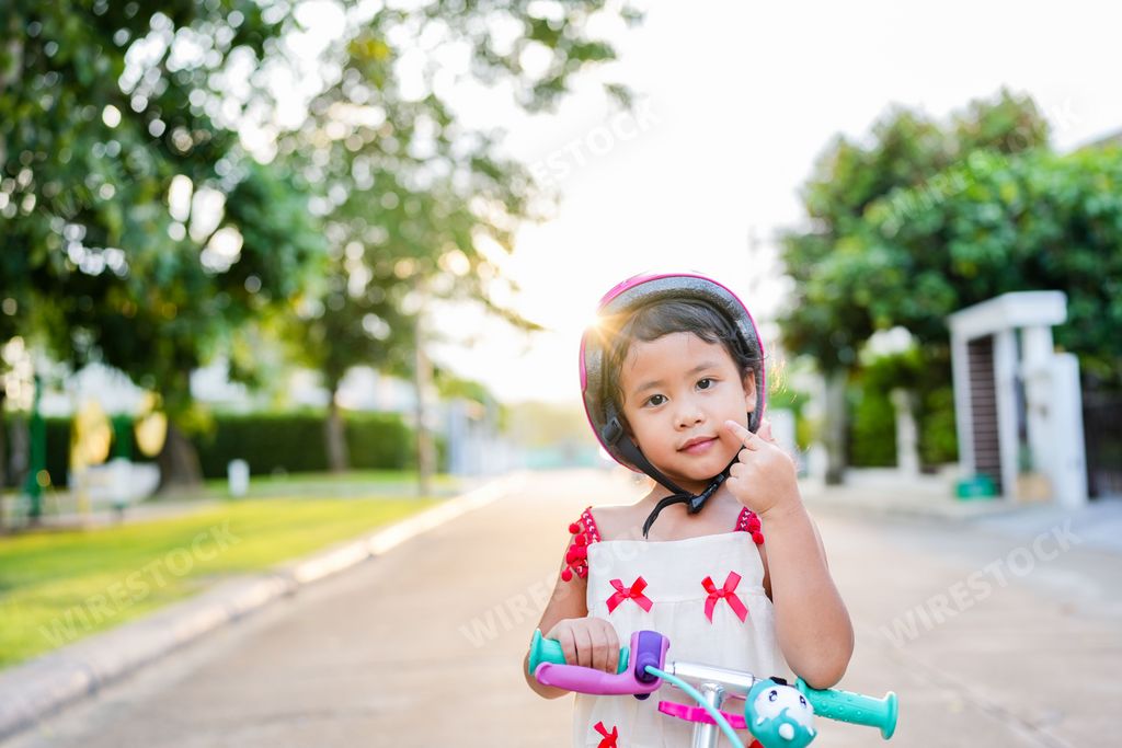 A closeup of a cute southeast Asian girl in a helmet on a scooter during sunset