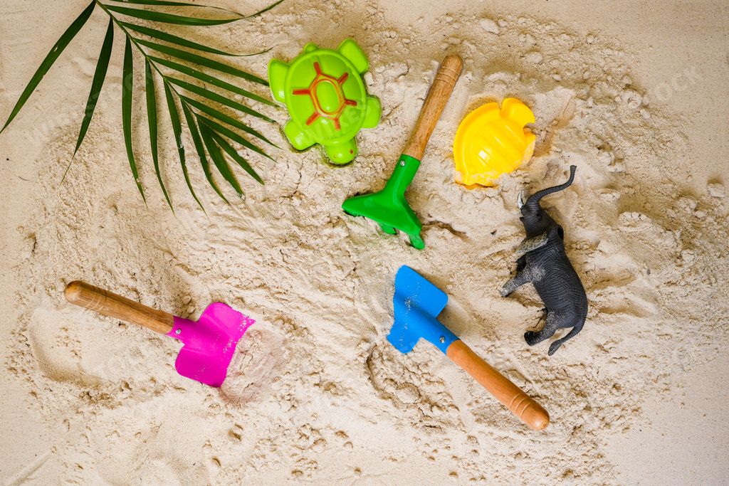 A flat lay of colorful sand toys including shovels and animals on the sand