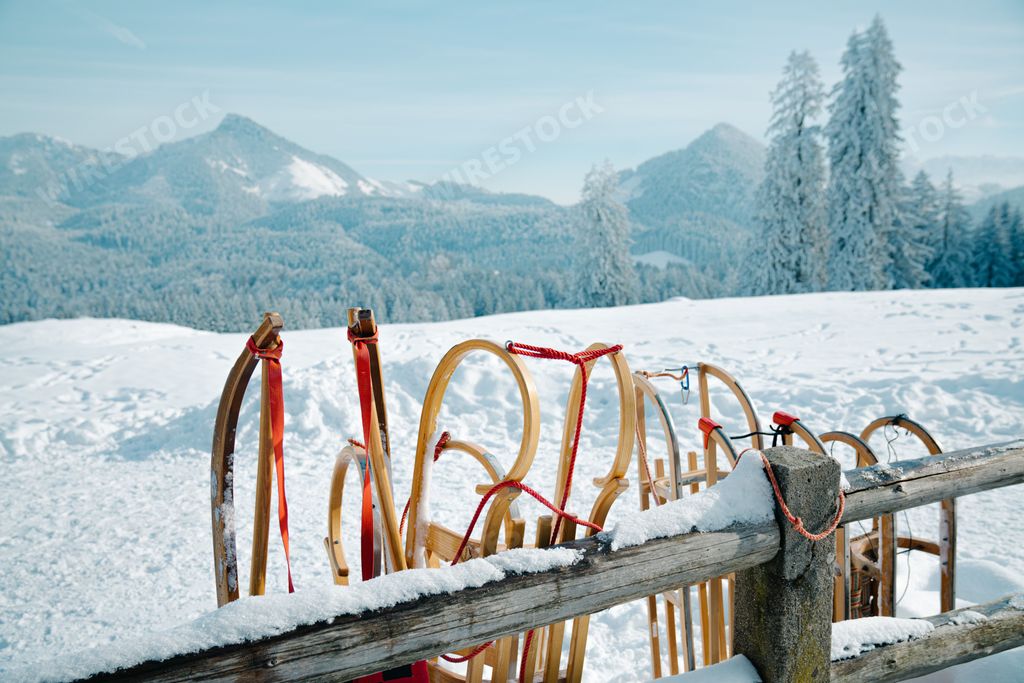 A sledding in snow-covered hillside with a wooden fence seen in the foreground