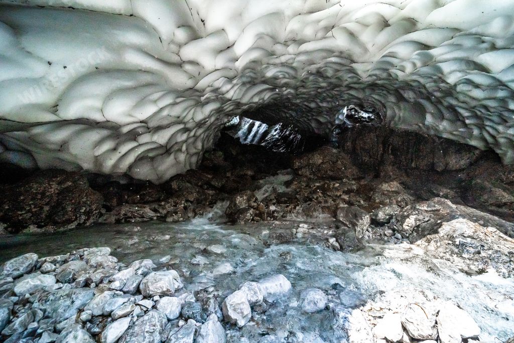 The opening of an ice cave with rocks in Kamchatka Peninsula, Russia