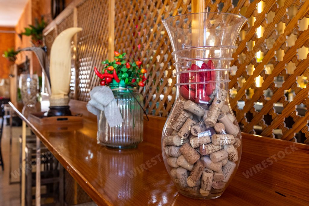 A vertical shot of a glass vase with wine corks and a vase with decorative flowers