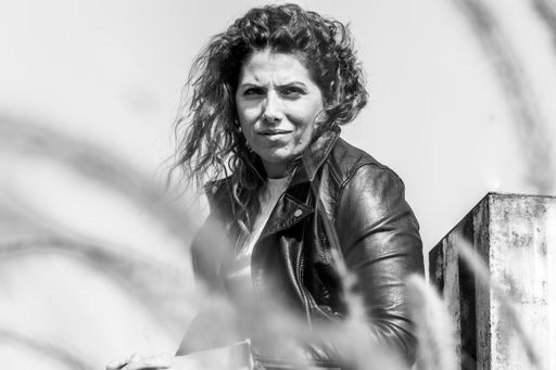 Grayscale shot of a Caucasian woman with curly hair posing in abandoned ...