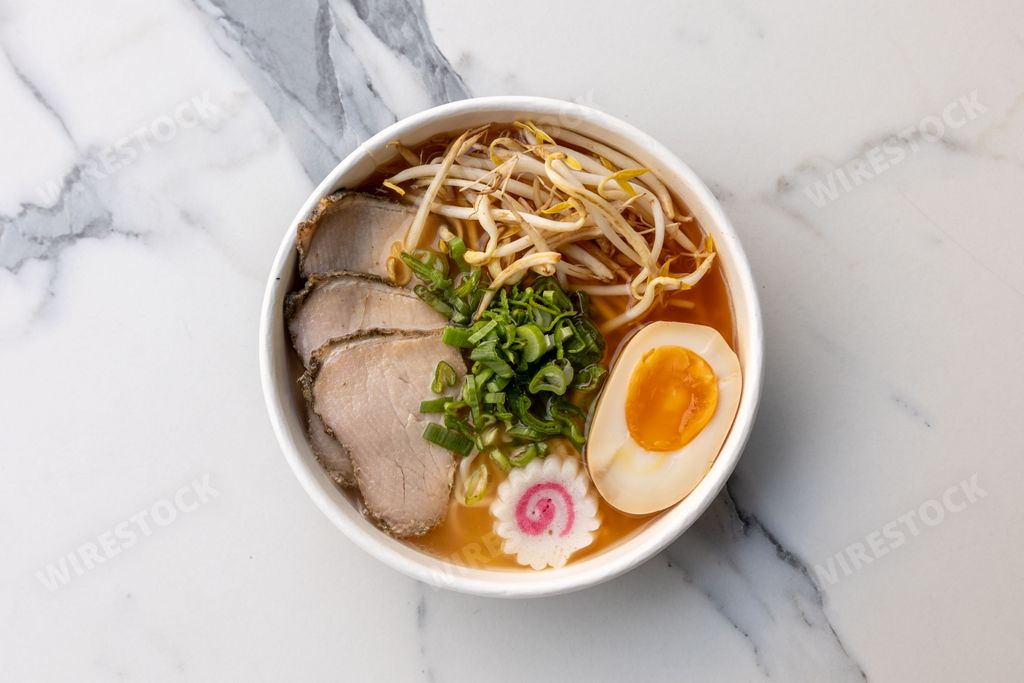 A top view of a delicious ramen bowl with beef and an egg served on the marble table