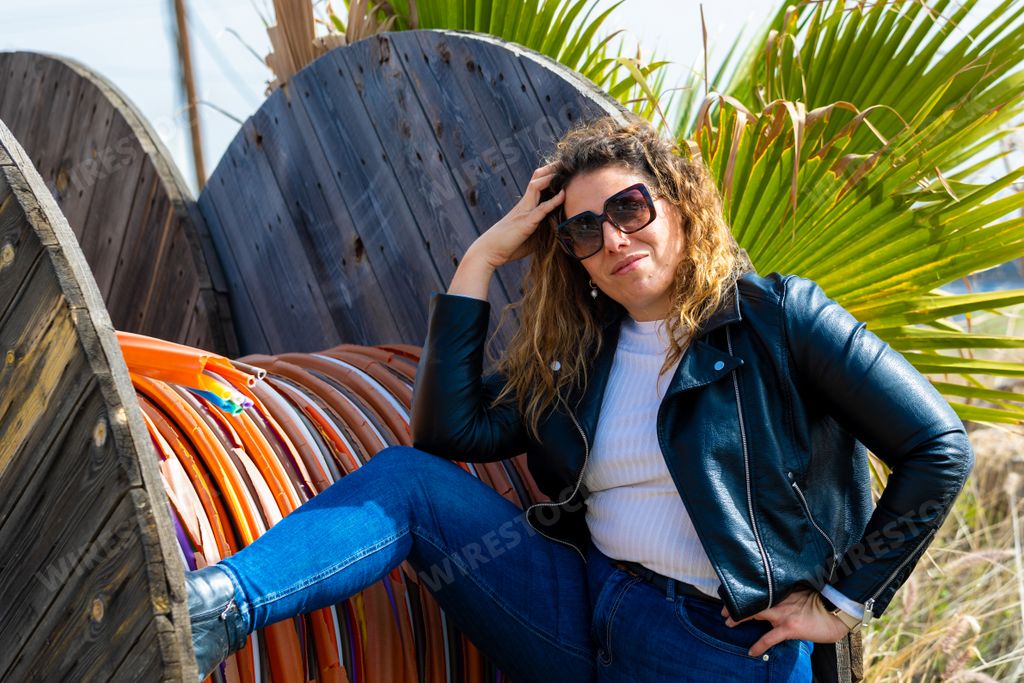 A Caucasian woman with sunglasses posing next to rotated colorful heat shrink tubing wires in the field