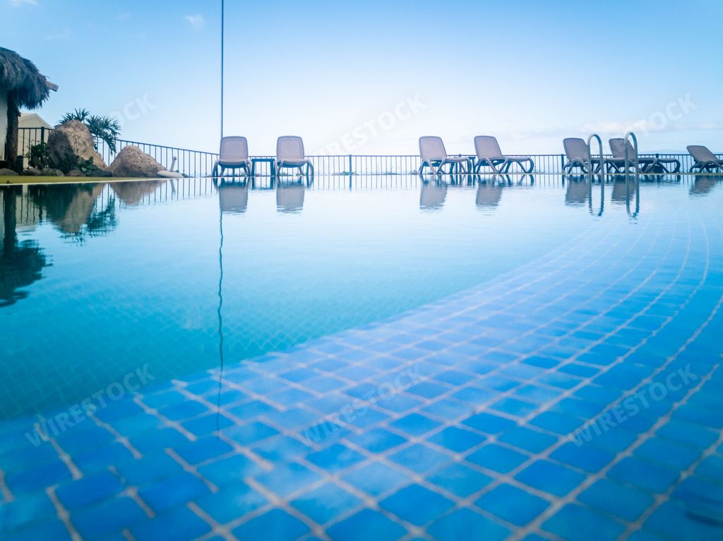 A view of a swimming pool reflecting beach chairs and an alcove