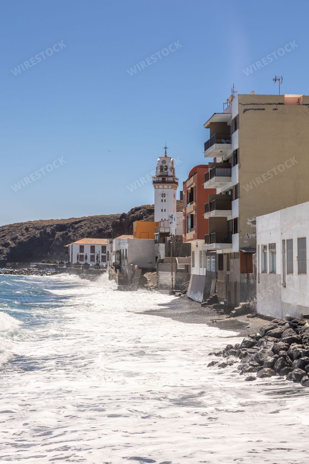 A beachfront town with a rocky cliffside, featuring multiple buildings overlooking the ocean